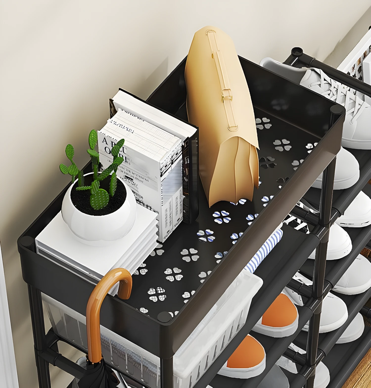 Zapatero multiusos negro con bolsa beige, libros, planta y paraguas en la parte superior.