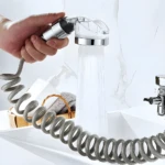 Extensor de grifo en espiral gris con ducha manual para lavabo, mostrando chorro de agua.