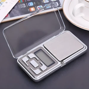 Gramera mini Zo portátil con tapa transparente, pantalla digital y botones de control, ideal para pesar pequeñas cantidades.