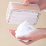 Jabonera con rodillos dispensando espuma en manos.