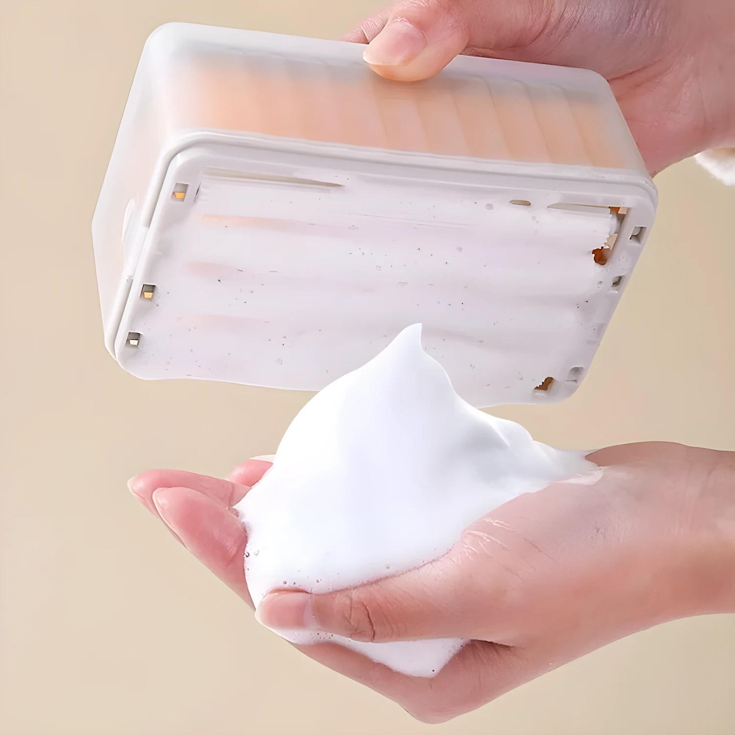 Jabonera con rodillos dispensando espuma en manos.