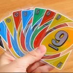 Mano sosteniendo cartas de Uno H2O: números 8, 6 y 9 en colores azul, verde, rojo y amarillo.
