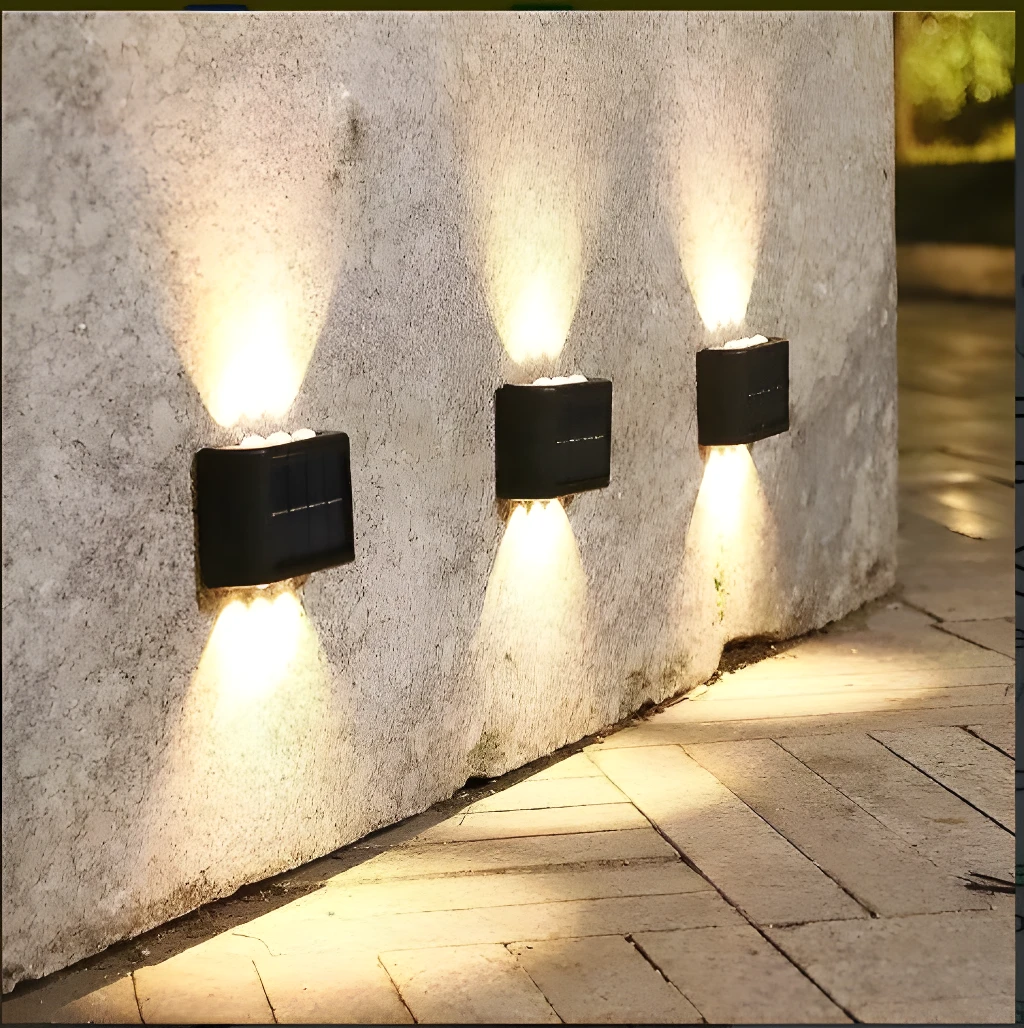 Lámparas solares de aplique LED que iluminan pared de concreto y camino de ladrillo.