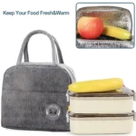 Lonchera térmica gris con compartimentos para comida y frutas, ideal para mantener alimentos frescos.