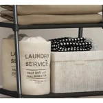 Organizador de ropa triangular con cestos y textiles en estantes de metal negro.