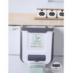 Papelera colgante blanca para cocina con dispensador de bolsas y diseño de frutas.