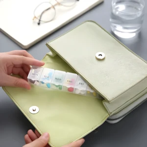 Pastillero semanal de 7 rejillas organizado dentro de un bolso verde claro.