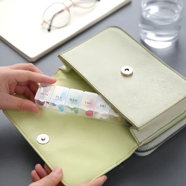 Pastillero semanal de 7 rejillas organizado dentro de un bolso verde claro.