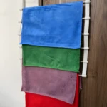 Perchero gancho para colgar toallas de microfibra de colores en puerta.