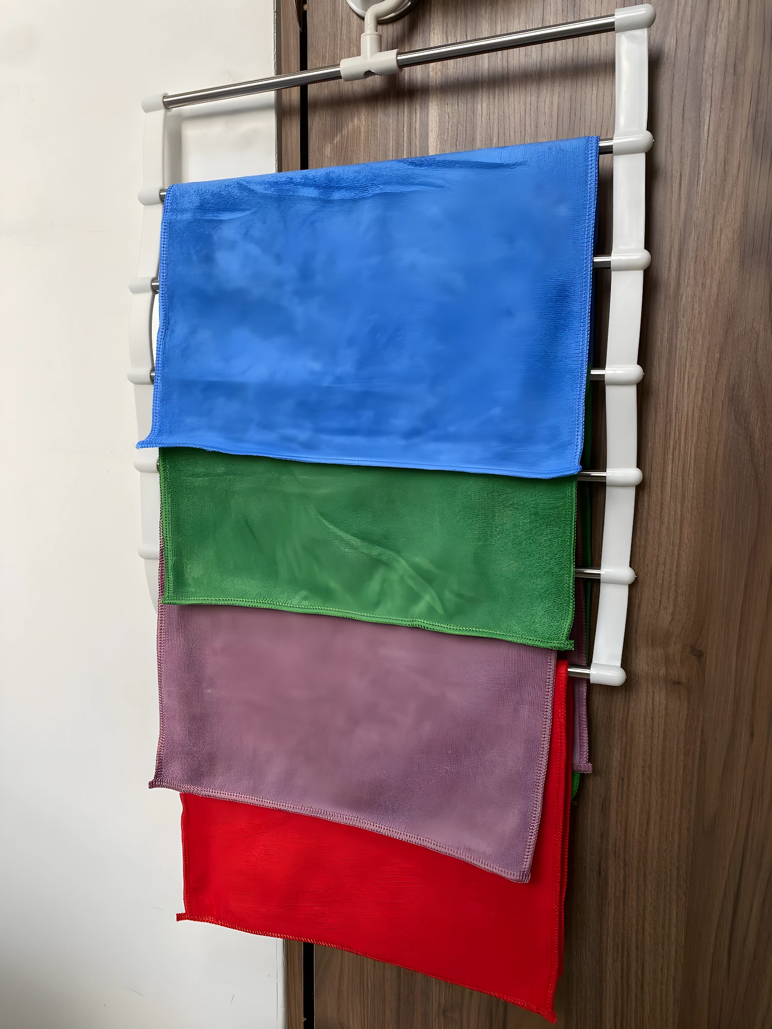 Perchero gancho para colgar toallas de microfibra de colores en puerta.