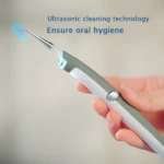 Removedor eléctrico de placa dental ultrasónico en mano, asegurando higiene oral.