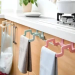 Soporte colgante para bolsa de basura en gabinetes de cocina y toalleros en color rosa y verde.