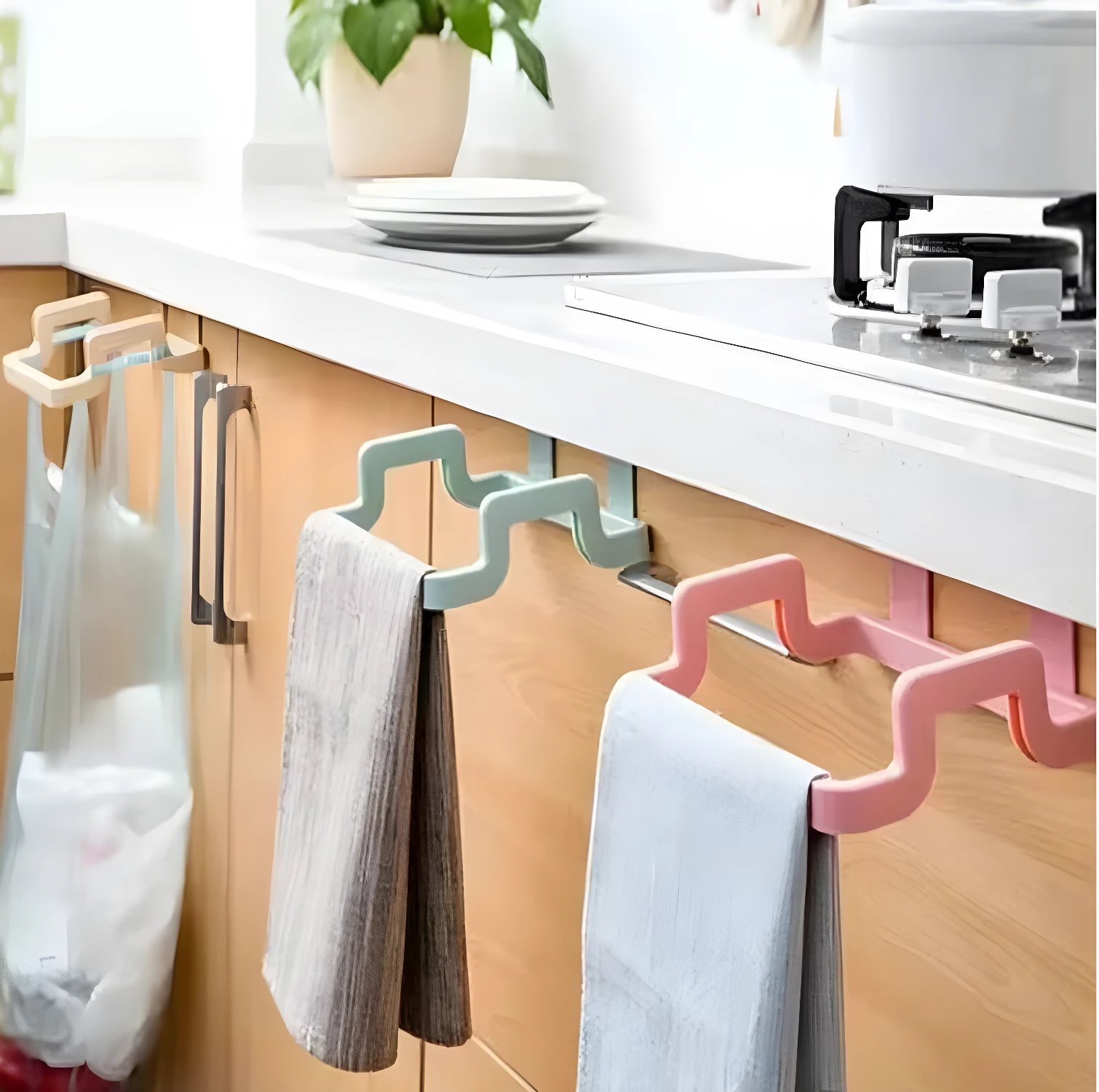 Soporte colgante para bolsa de basura en gabinetes de cocina y toalleros en color rosa y verde.