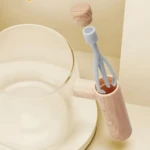 Taza mezcladora eléctrica con tenedor gris y tapa de madera flotando sobre base redonda.