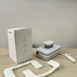 Limpia vidrios magnético doble cara con almohadillas blancas y cuerda de seguridad en mesa de madera.