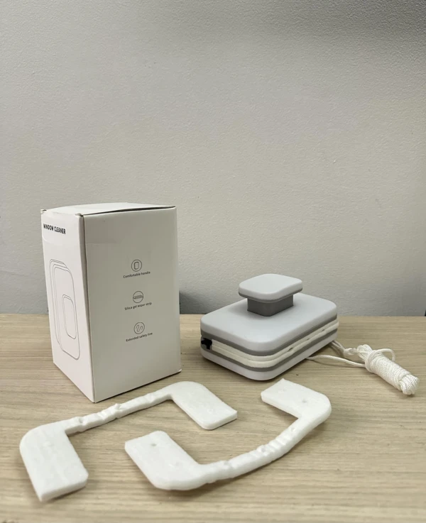 Limpia vidrios magnético doble cara con almohadillas blancas y cuerda de seguridad en mesa de madera.