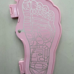 Tapete masajeador de pies rosado con reflexología podal detallada para alivio y bienestar.