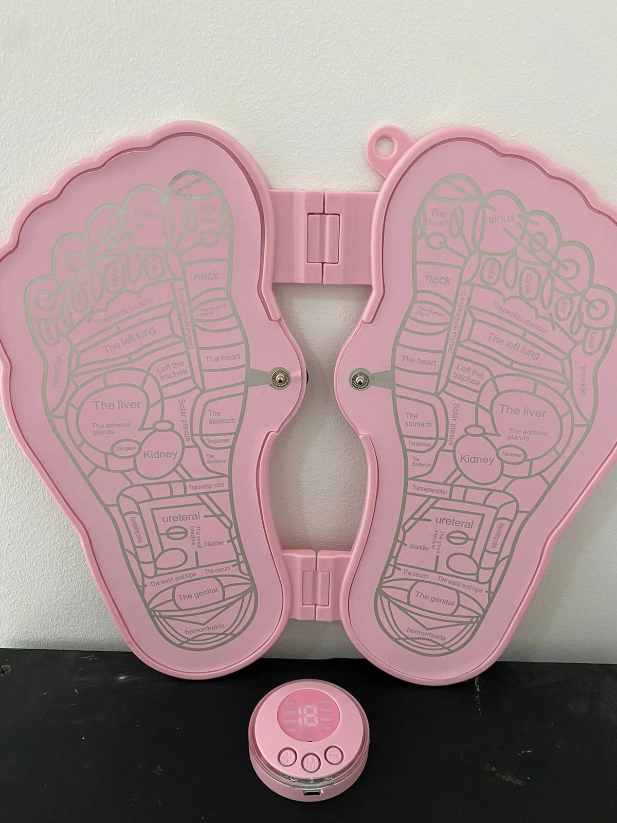 Tapete masajeador de pies rosado con diagrama de puntos de reflexología, ideal para terapia.