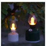 Linterna LED de camping humidificadora colgando de rama, luz cálida.