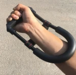 Ejercitador de mano, muñeca y antebrazo de resorte negro en uso por persona.