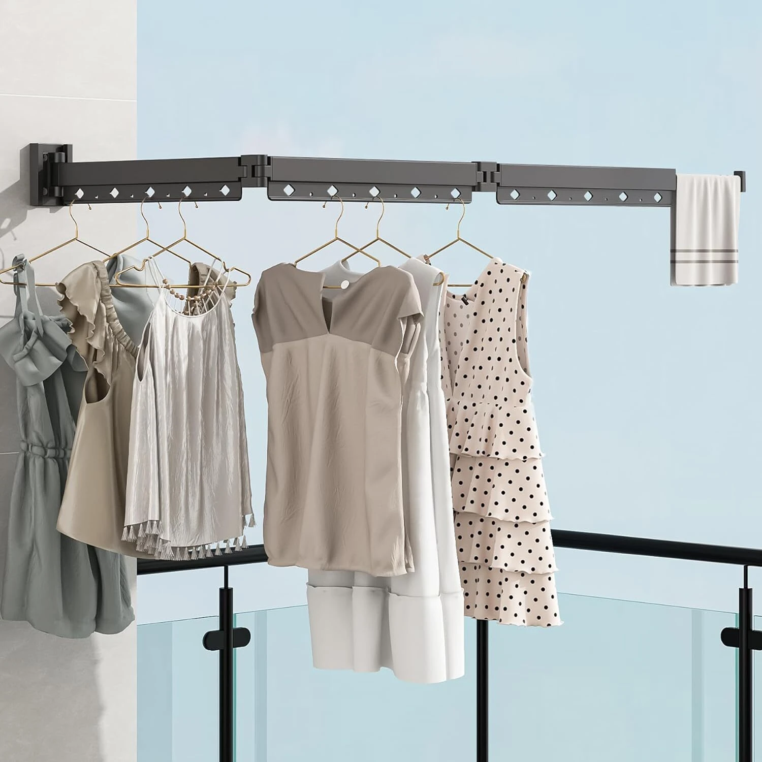 Tendedero plegable de pared gris con 5 prendas colgadas y toalla, ideal para balcones.