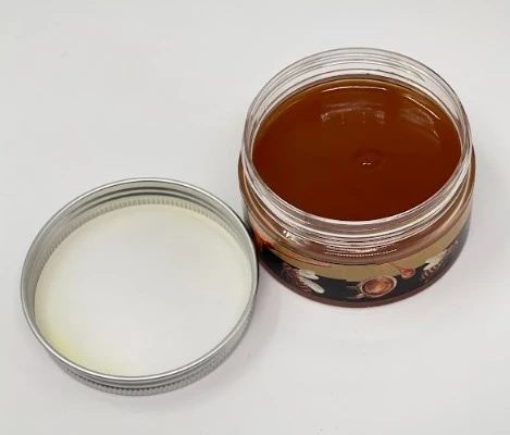 Reparador de Madera Bee Repair en frasco abierto, líquido café y tapa plateada al lado.