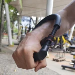 Ejercitador de mano y muñeca de hombre, con pesas de gimnasio al fondo.