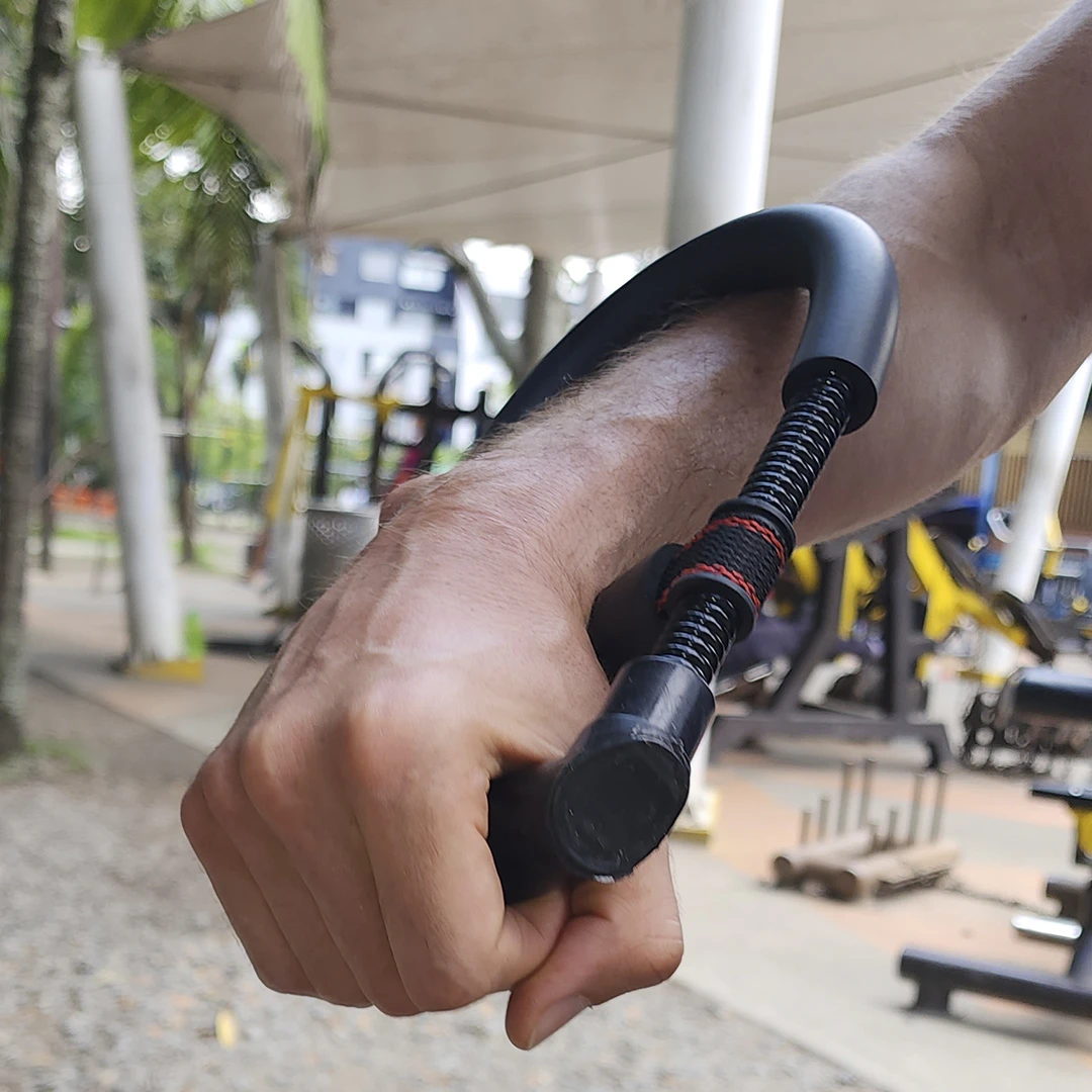 Ejercitador de mano y muñeca de hombre, con pesas de gimnasio al fondo.