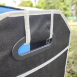 Organizador para carro o camping negro con manija y detalles blancos, visto desde un ángulo cercano.