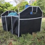 Organizador de carro y camping negro con divisiones y asas resistentes, ideal para organizar objetos.