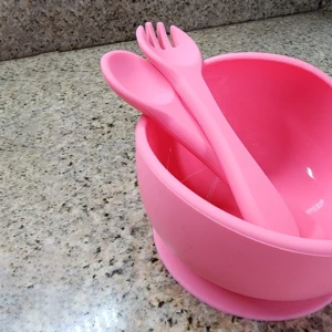 Vajilla de silicona rosa para bebé con cuchara y tenedor dentro del bol.