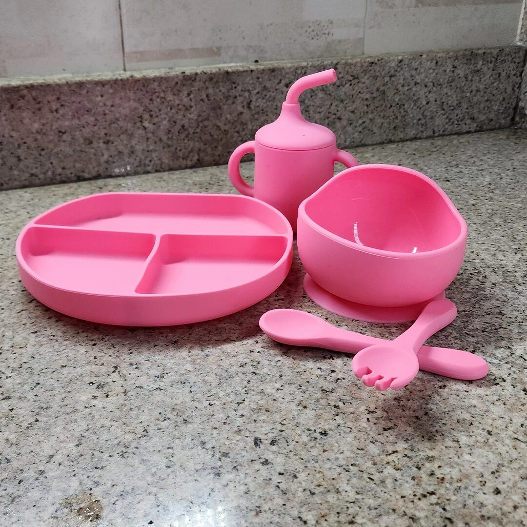 Vajilla de silicona para bebé rosa: plato con divisiones, tazón con ventosa, vaso y cubiertos.
