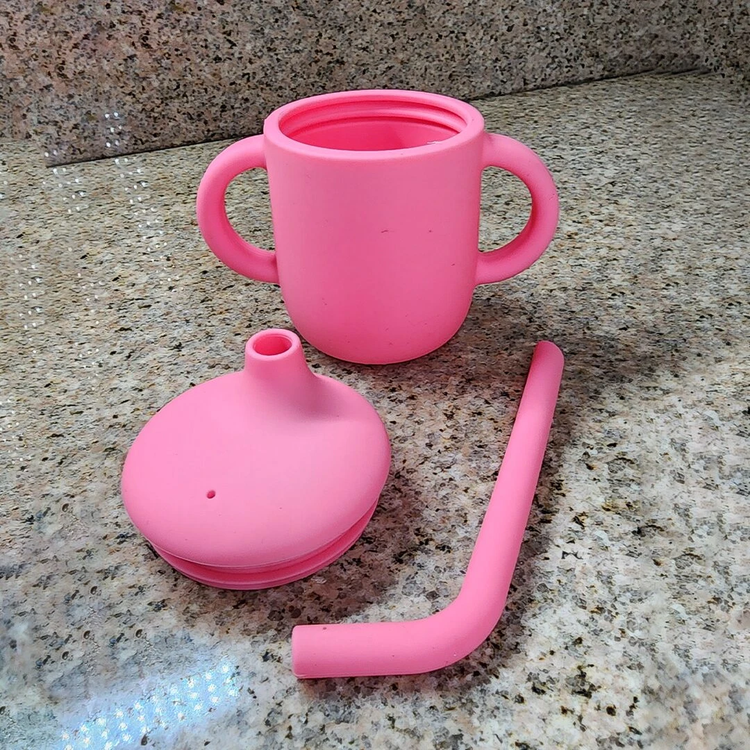 Taza de silicona para bebé color rosa con tapa y pitillo.