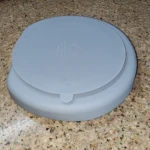 Vajilla de silicona para bebé, plato gris con tapa en superficie texturizada.