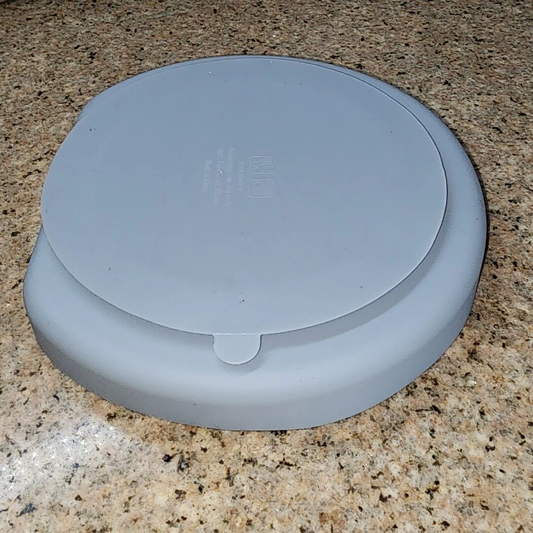 Vajilla de silicona para bebé, plato gris con tapa en superficie texturizada.