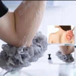 Persona lavándose el brazo con esponja corporal de ducha gris.