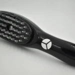 Cepillo Terapia Capilar Spa negro con cerdas suaves y botones de control, ideal para el cuidado del cabello.