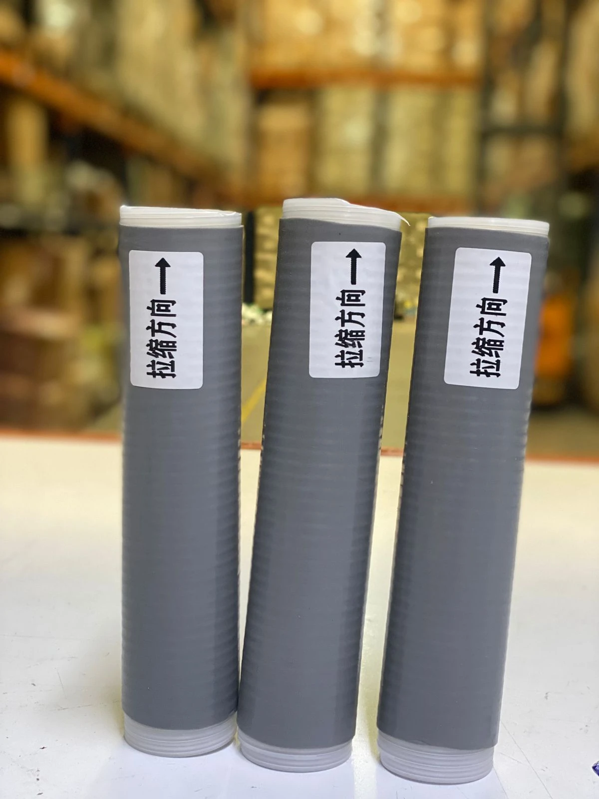 Tres fundas de silicona grises para ollas, con etiquetas de dirección de estiramiento.