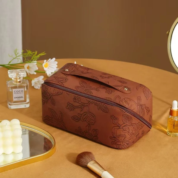Cosmetiquera texturizada marrón con estampado floral, ideal para organizar maquillaje y accesorios.