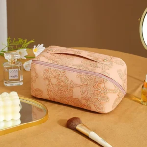Cosmetiquera texturizada con diseño floral, Chanel y brocha de maquillaje.
