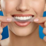 Tiras blanqueamiento dental 3D White aplicadas en los dientes superiores de una mujer sonriendo.