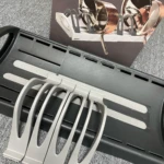 Organizador de ollas ajustable en gris sobre alfombra, con ollas de cobre en la caja.