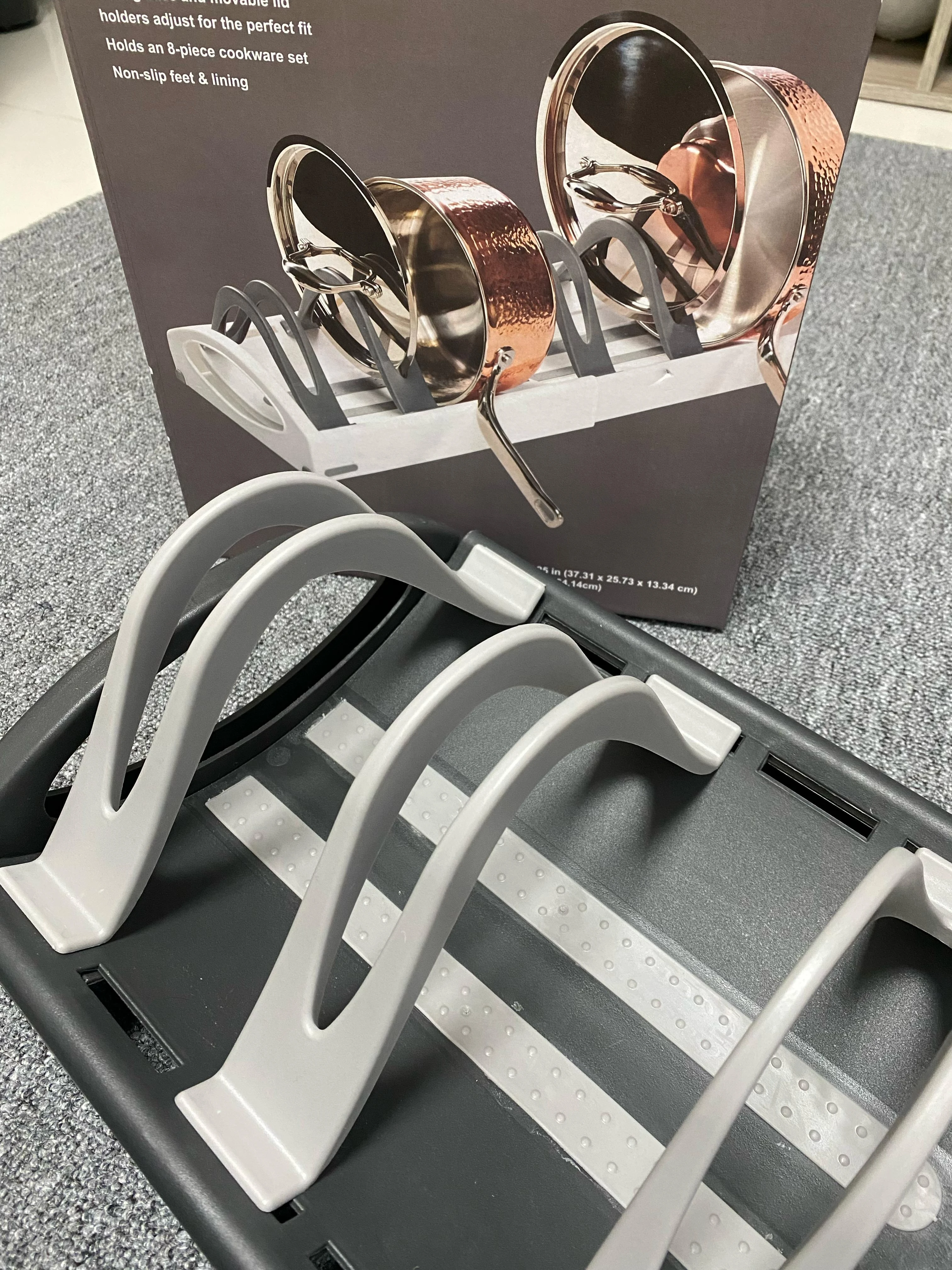 Organizador de ollas ajustable gris con compartimentos para utensilios de cocina.