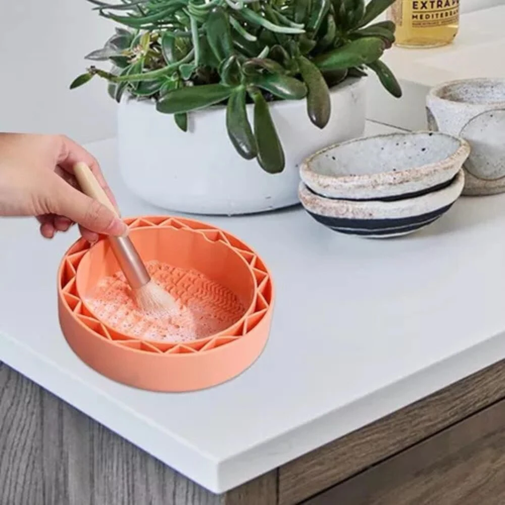 Limpiador de brochas A2406-274 con cepillo en tazón naranja espumoso, sobre encimera blanca.