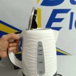 Tetera hervidor de agua blanca 1.7L ICM con medidor, tapa abierta y mano sujetando el asa.