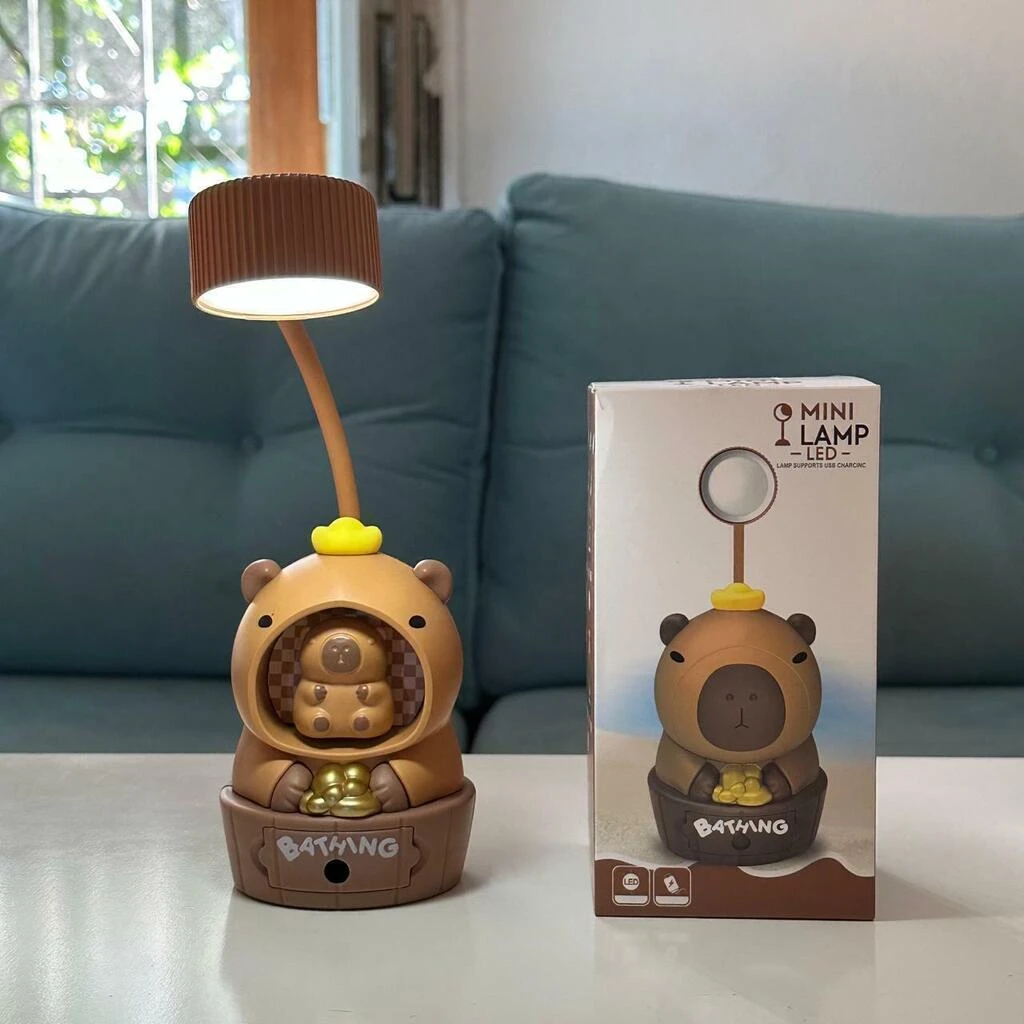 Lámpara capibara adorable con luz LED, en su base tipo tina y caja del producto.