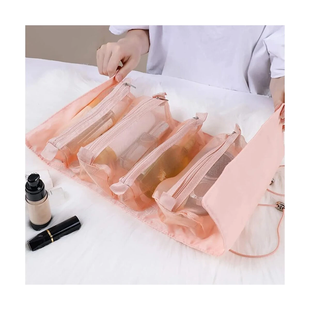 Cosmetiquera viajera desenrrollable en color rosa con compartimentos transparentes y productos de belleza.