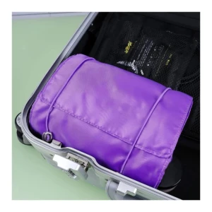 Cosmetiquera viajera desenrrollable morada dentro de maleta plateada con cierre de combinación.