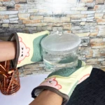 Guantes para hornear de silicona con diseño de oso sosteniendo una olla de vidrio hirviendo.