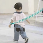 Arnés muñequera anti pérdida niño con correa espiral azul, caminando al aire libre.